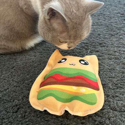 Katze schnuppert an Spielfigur für Katzen aus Stoff aus der Kawaii Food-Kollektion, Design Burger Cat