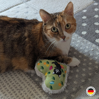 Katzenspielzeug in Form des Lucy-Plüschherzens liegt neben Katze